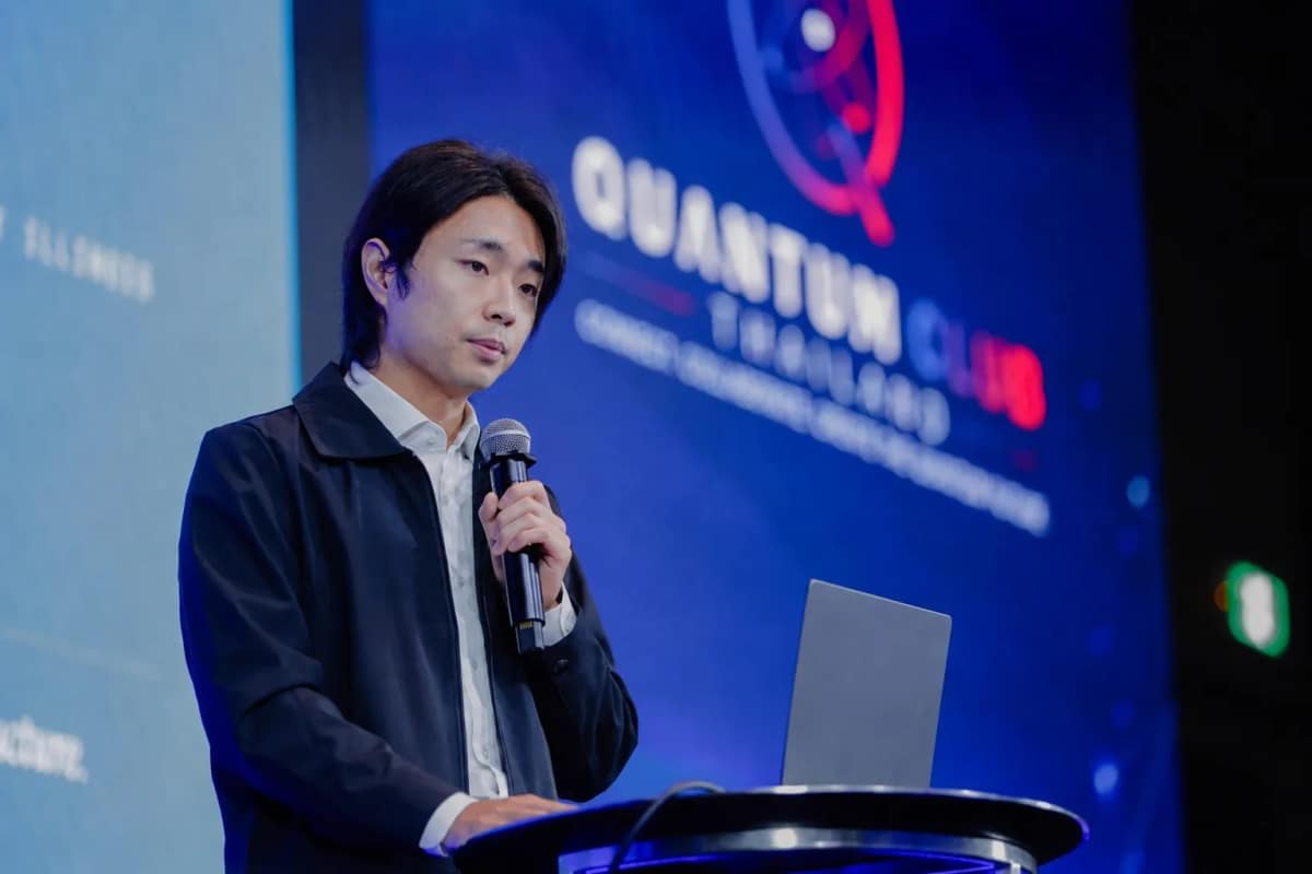 qBraid COO Ricky Young speaking at a podium with a laptop during the live quantum demonstration